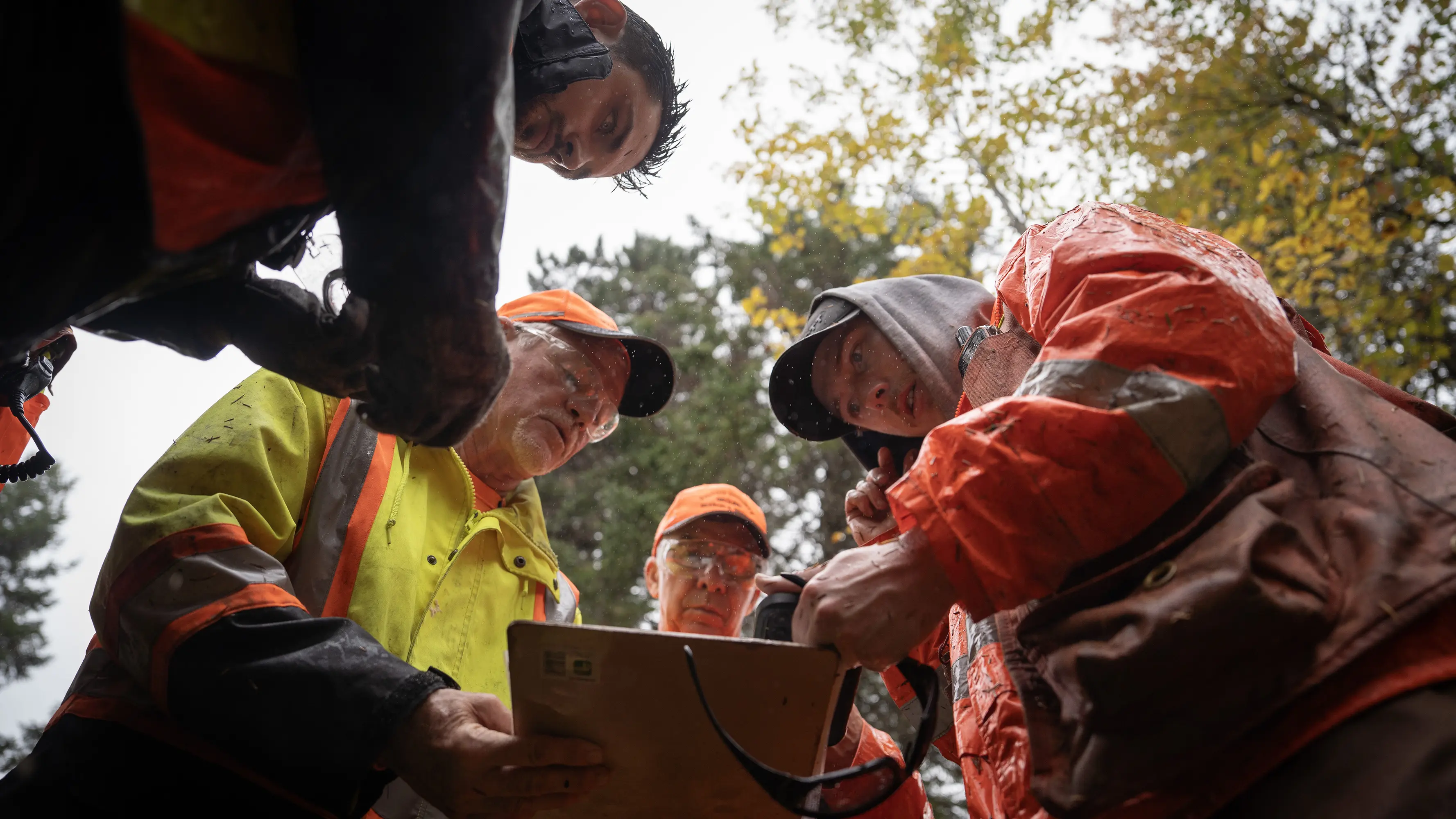 A group of volunteers huddled around a clipboard reviewing a map. They are all intently listening to one person talk.