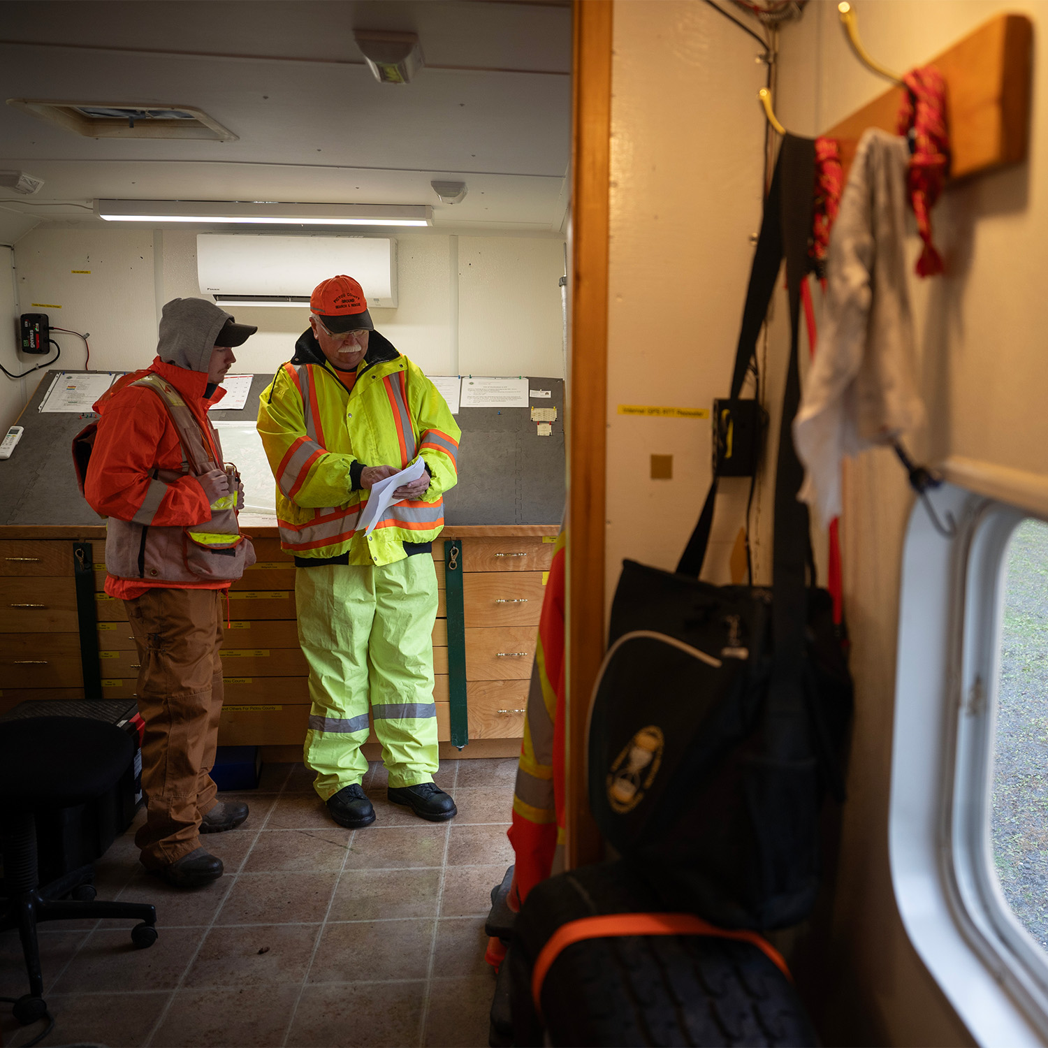 Two people stand inside the incident command post reviewing some papers.