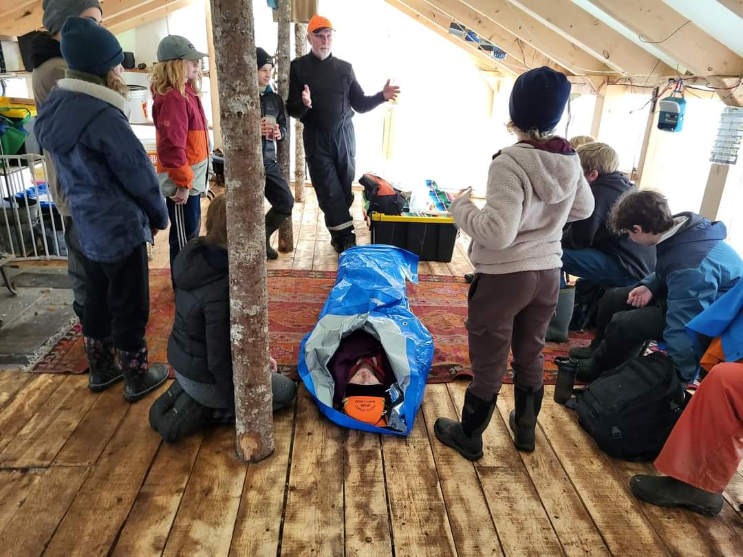 A team member gives a demonstration of how to wrap someone in a thermal 'burrito'.